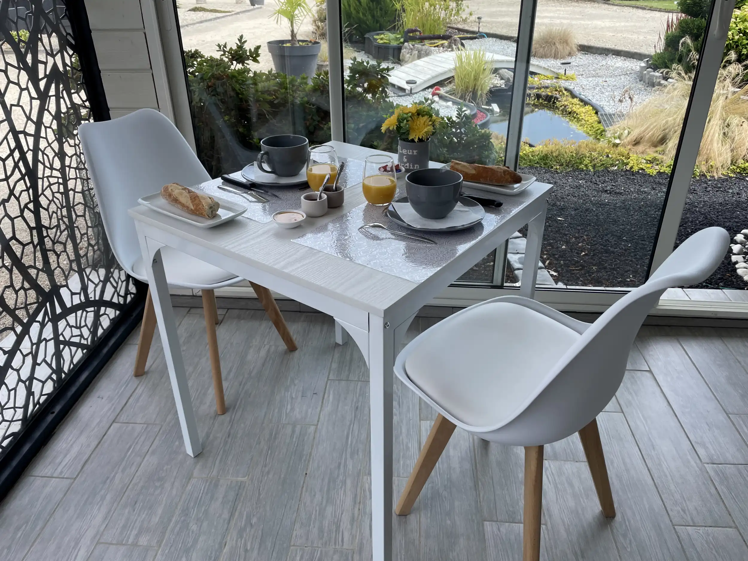Table dressée pour le petit-déjeuner dans la véranda de L’Escale Arc-en-Ciel, face au jardin japonais