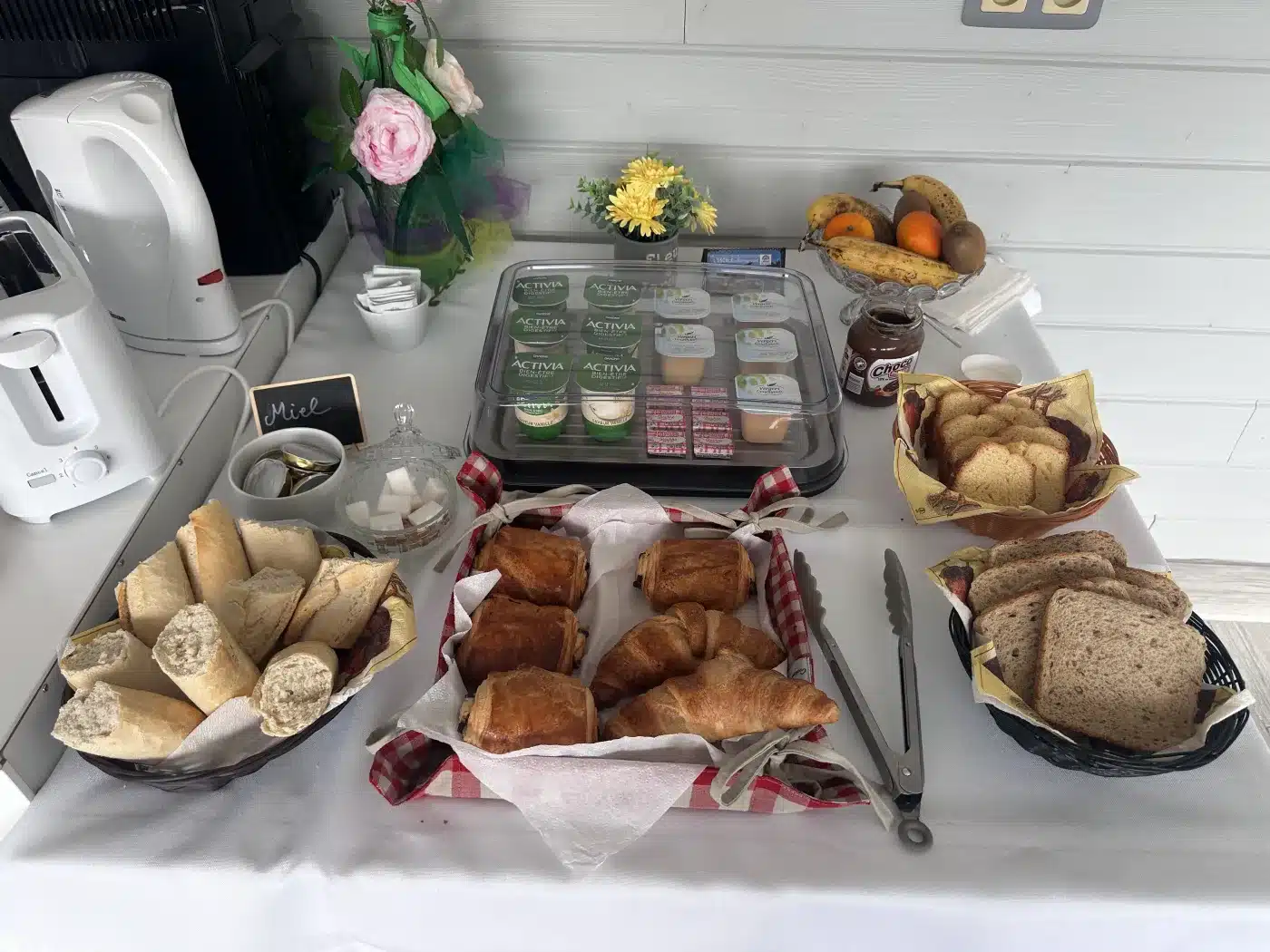 Buffet du petit-déjeuner : pains, viennoiseries, yaourts, fruits et boissons, à L’Escale Arc-en-Ciel