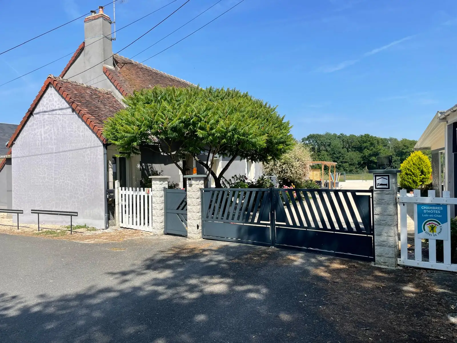 L’entrée de la maison d’hôtes L’Escale Arc-en-Ciel, son portail et son arbre